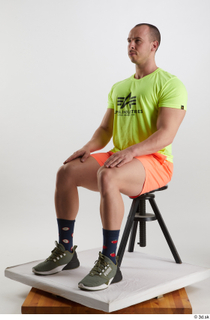 Joel  1 dressed green sneakers orange shorts sitting sports…
